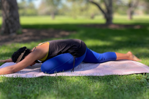 Breanna smiling with her eyes closed as her left arm reaches overhead in a side body stretch.
